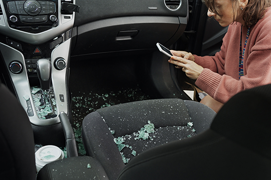 IMAGE: Woman taking photos inside car after a break-in