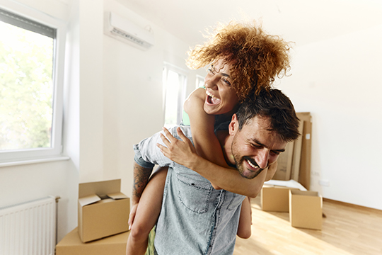 IMAGE: Couple laughing inside new home with boxes in background