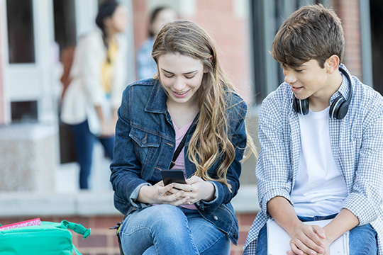 IMAGE: Young woman and man looking together at her phone