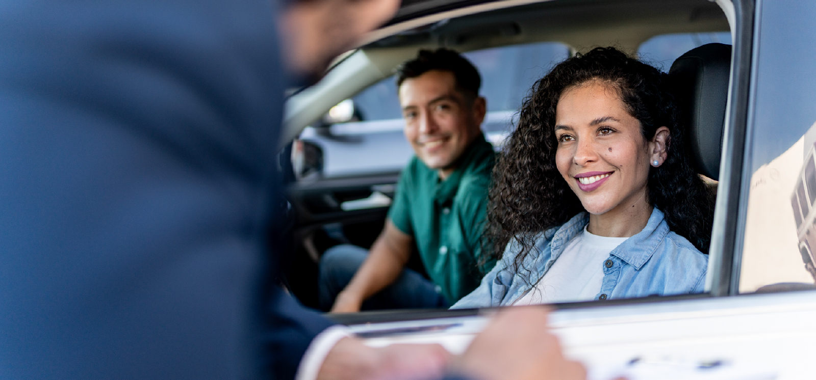 IMAGE: Couple sitting in car and smiling at salesperson