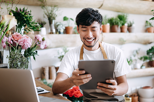 IMAGE: Man working in a florist's shop looking at a tablet