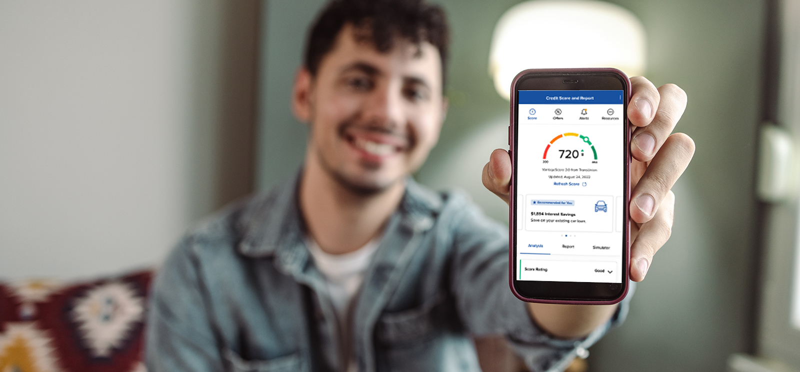 IMAGE: Smiling man holding a phone with SavvyMoney's Credit Score displayed