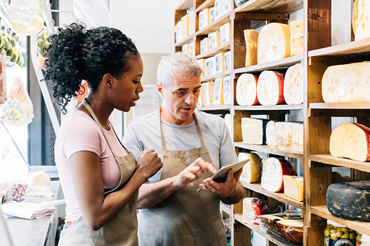 IMAGE: Two people inside a cheese shop looking at inventory with tablet