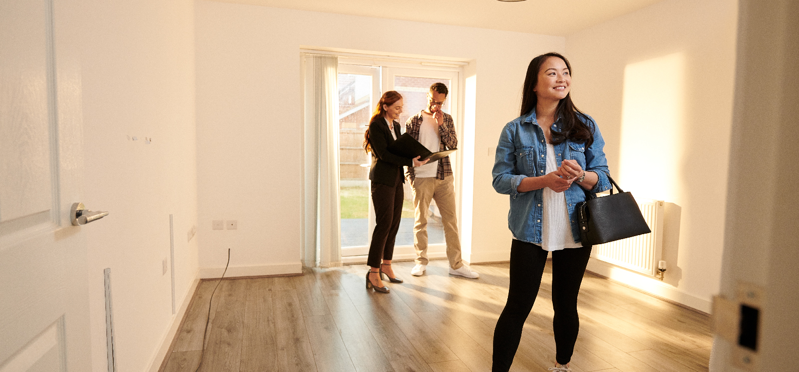 IMAGE: Couple talking with realtor inside empty home