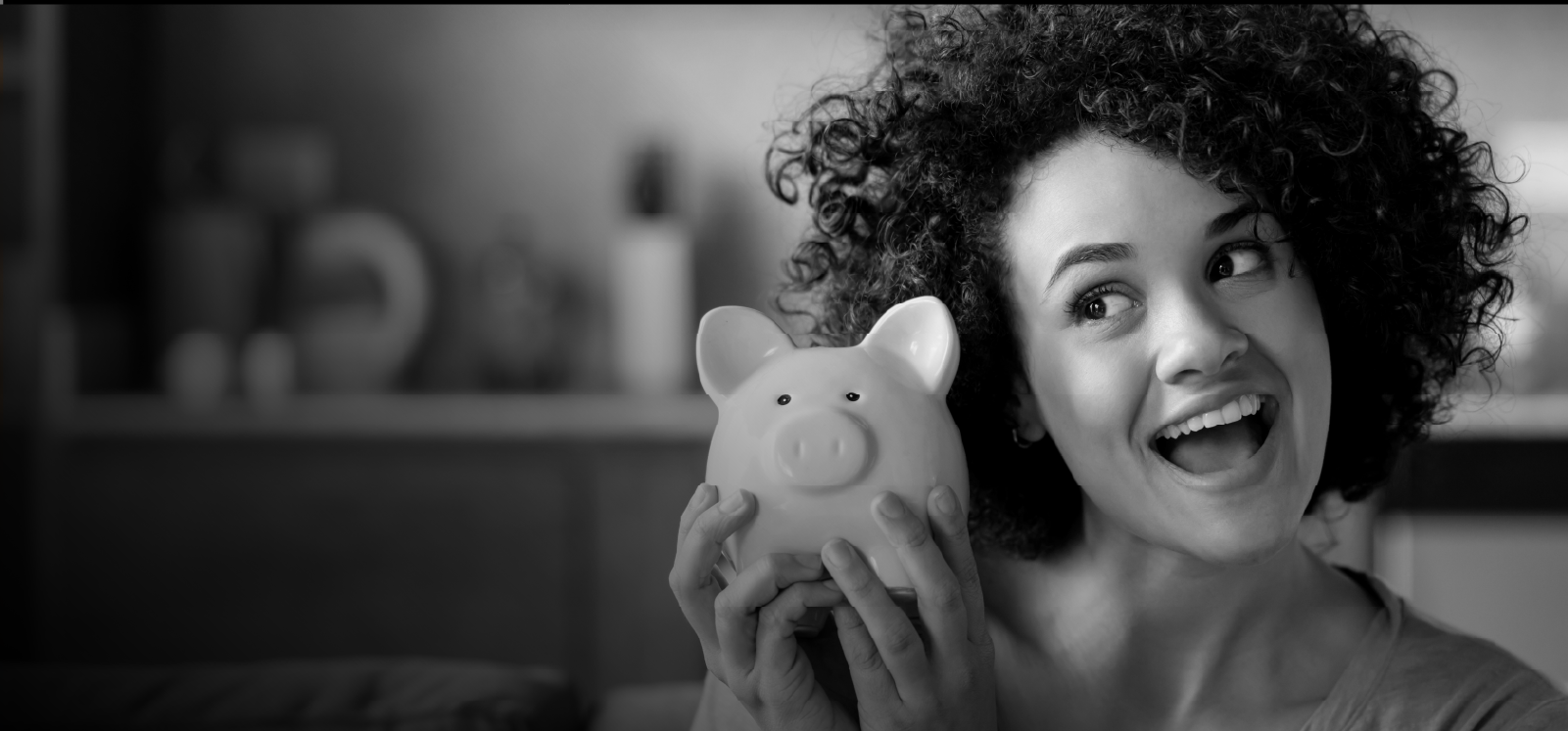 IMAGE: Woman smiling while holding a piggy bank