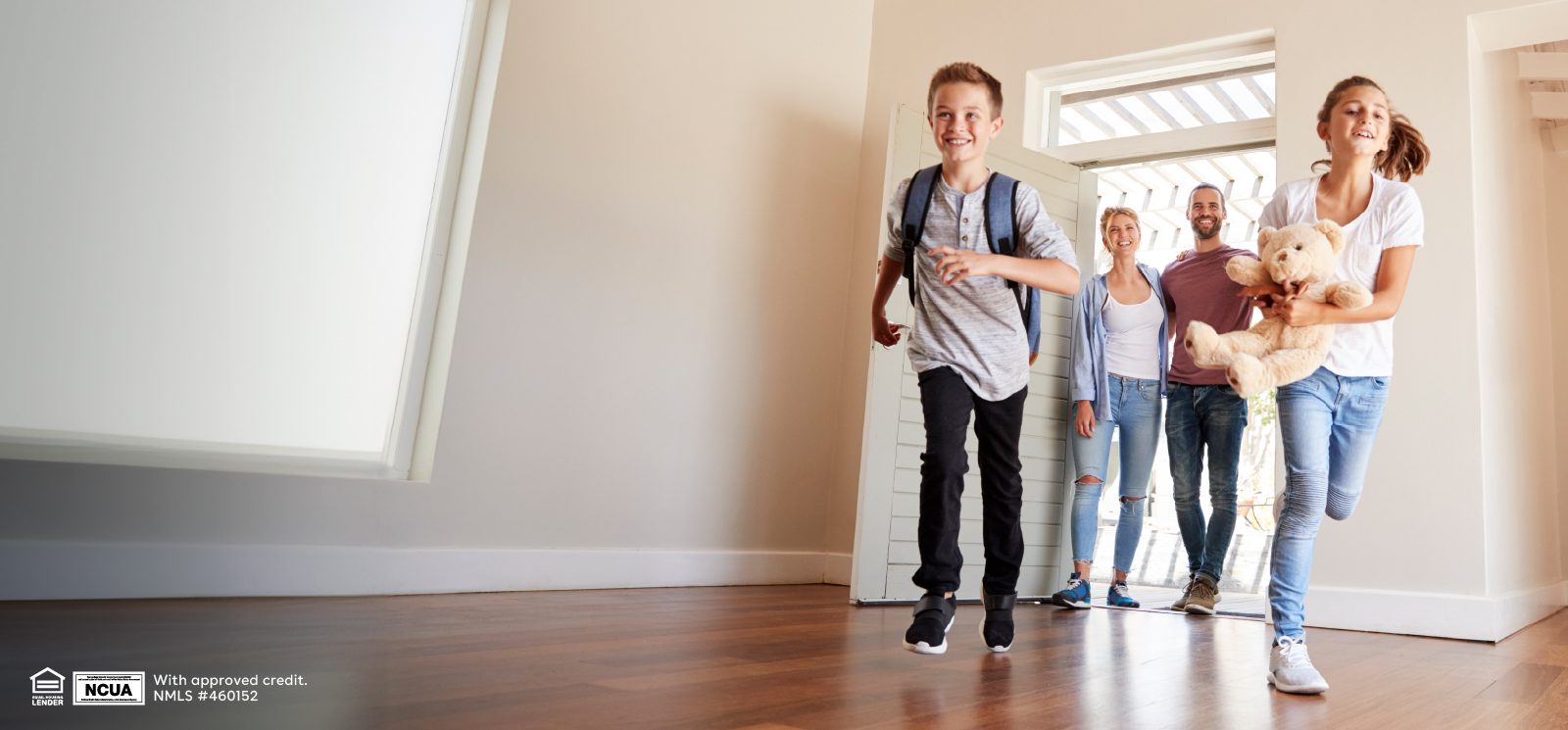 IMAGE: Kids running into new, empty house with parents standing behind smiling