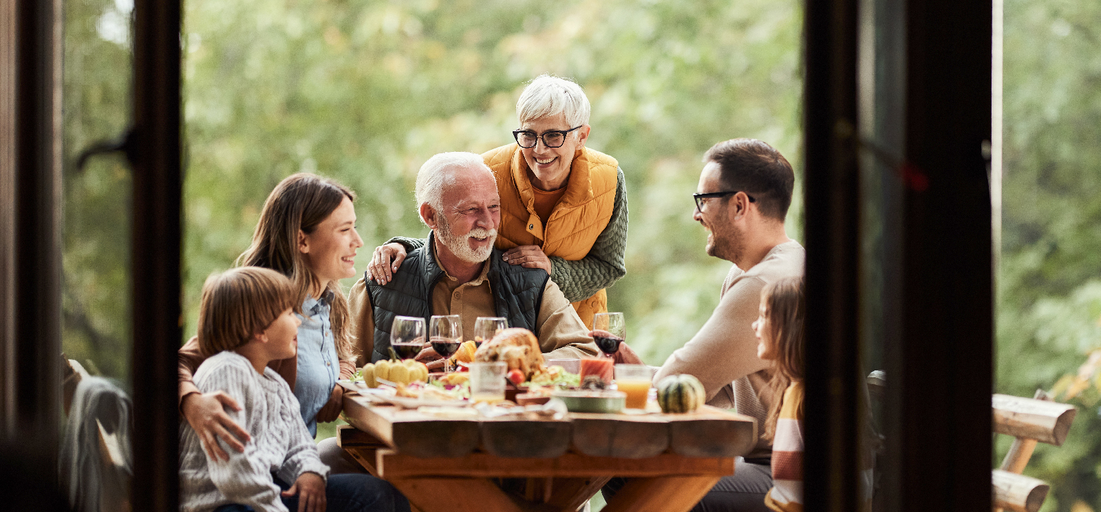 IMAGE: Multi-generational family outside sitting at a table for a meal